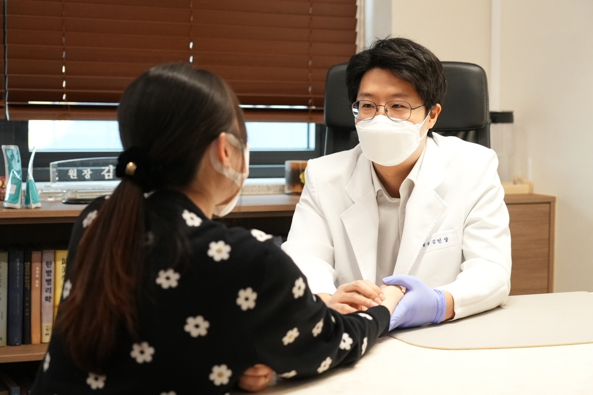 생기한의원 천안아산점 김민상 대표원장이 내원객의 손을 살피며 상담하는 모습