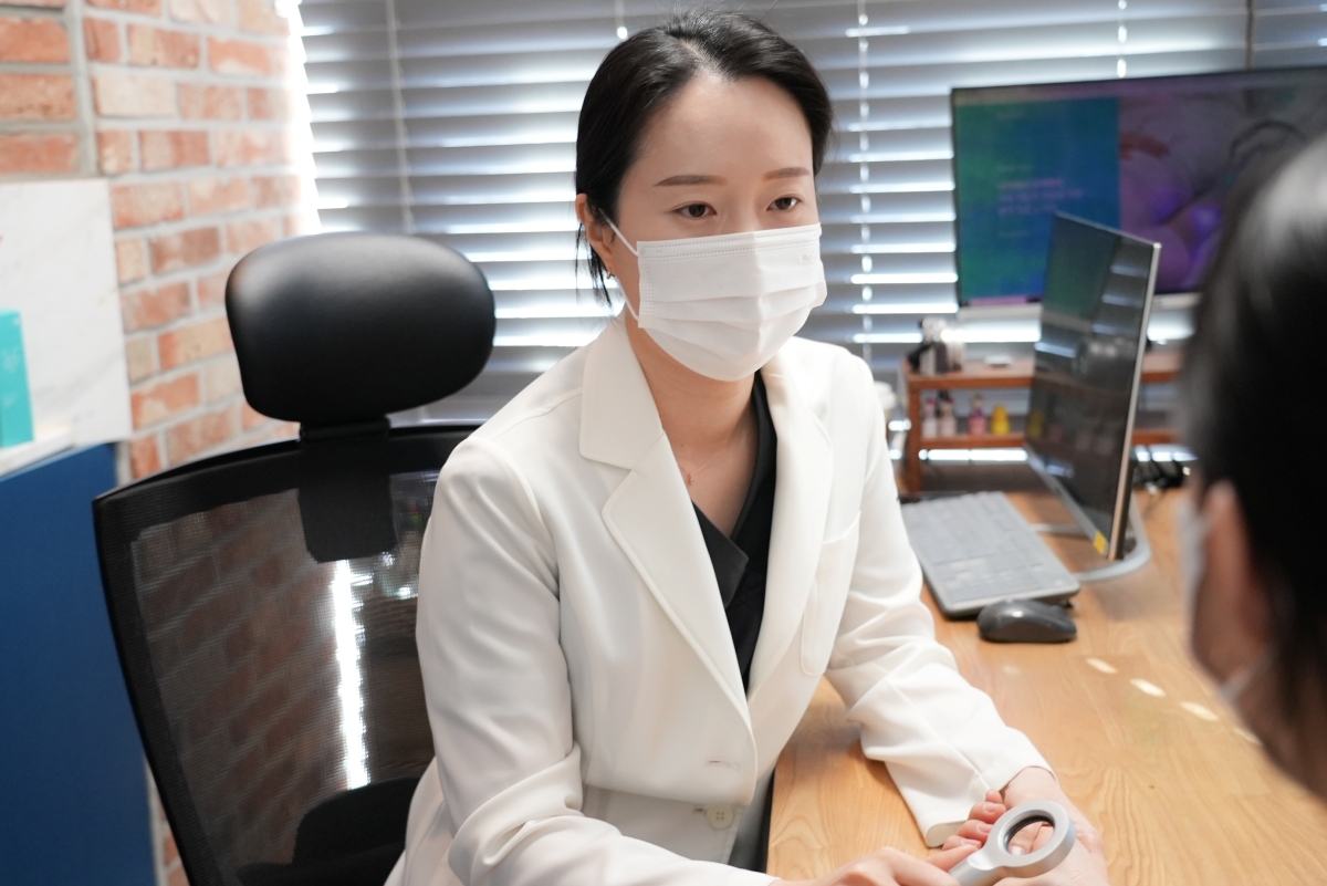 표가나 대표원장이 진료실에서 내원객과 이야기를 나누며 증상을 살핍니다.